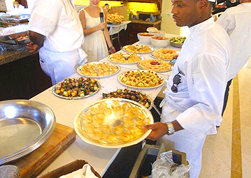 Frank, catering staff for Metro City 
            Wings Catering, placing down additional platters of hors d'oeuvres for the 
            P. Diddy's All White 4th of July event.